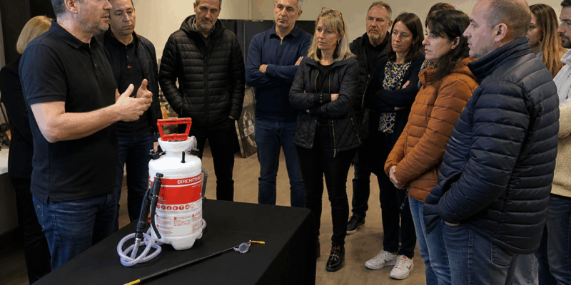 Formateur en lutte antiparasitaire présentant un pulvérisateur professionnel à des stagiaires