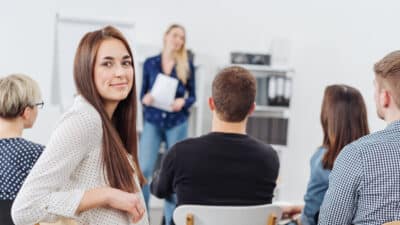 Jeune femme dans une formation Izipest se tournant pour sourire à la caméra vue du fond de la salle