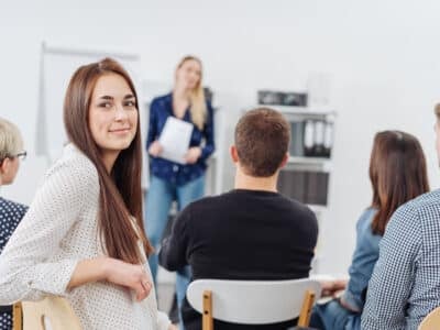 Jeune femme dans une formation Izipest se tournant pour sourire à la caméra vue du fond de la salle