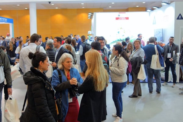 Des personnes se tiennent debout en plusieurs petits groupes à l’intérieur devant des stands