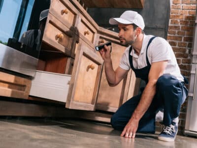 Opérateur de lutte antiparasitaire examinant la cuisine avec une lampe de poche