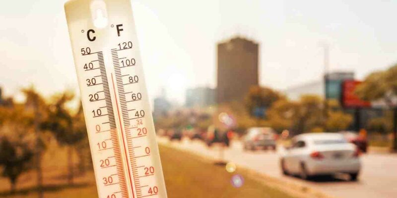 Thermomètre devant une scène urbaine pendant la canicule